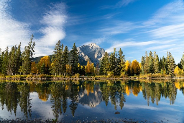 A beautiful day in Banff National Park with calm water and beautiful trees.