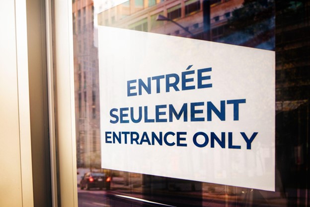 Bilingual official entrance sign taped to a glass door in Montreal
