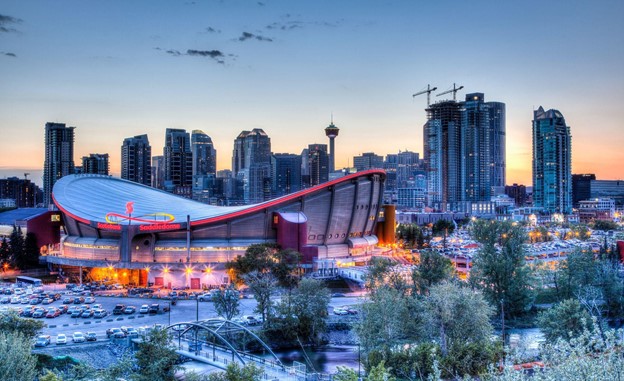 Sunset over Calgary’s skyline with the Scotiabank Saddledome in the foreground. The dome with its unique saddle shape is home to Calgary Flames NHL Club.