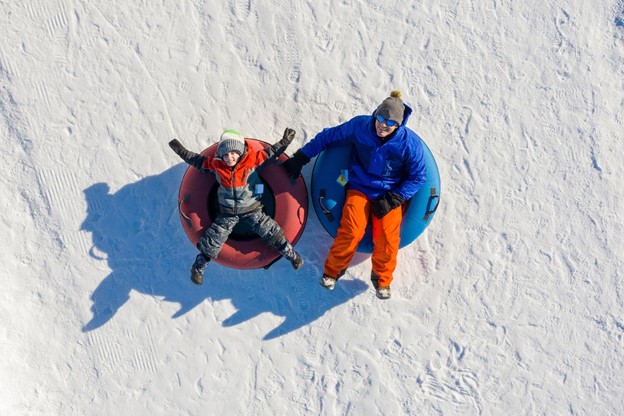 Father and son snow tubing in the winter in Canada