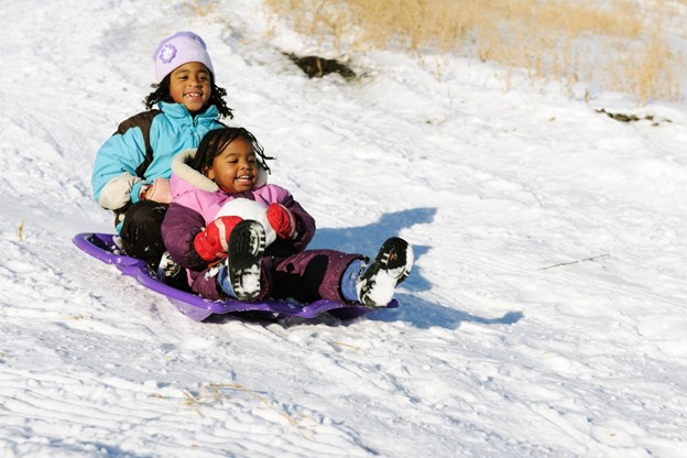 Girls having fun and laughing in the snow on a toboggan
