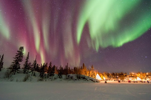 A group of people gazing upon the Northern Lights in Ontario, Canada.