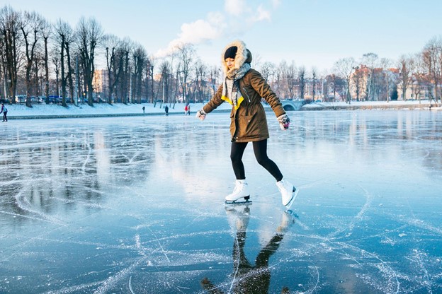 A young woman ice skating on a frozen lake in the sunset