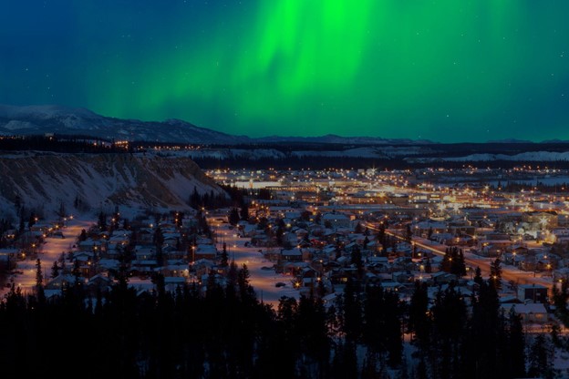 Strong northern lights (Aurora borealis) emerge in the night sky over downtown Whitehorse, capital of Yukon, Canada, in winter.