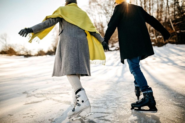 A couple ice skating on a sunny day in winter