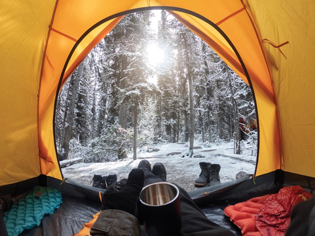 Person winter camping in a tent in the snow